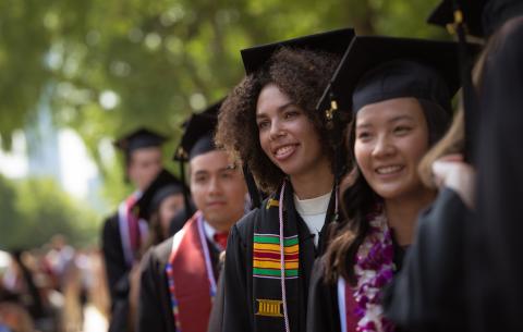 Image of undergraduates lined up to receive their diplomas. They are smiling.