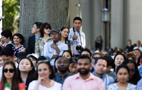 Image of proud families and friends watching the OneMIT Commencement Ceremony. One guest has his thumb up.