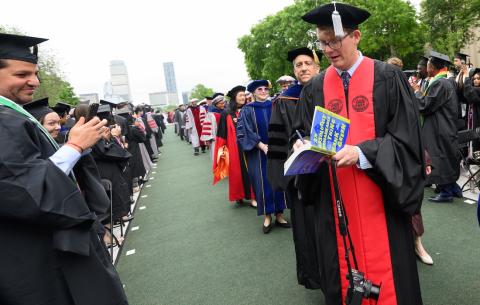 Image of Hank Green processing into Killian Court signing someone's book