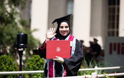 Image of a graduate walking with her diploma at the Undergraduate Ceremony