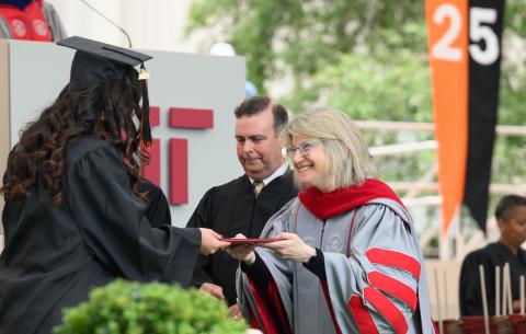 Image of President Sally Kornbluth handing a graduate her diploma case
