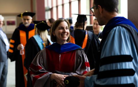 Image of faculty members in their regalia talking before the OneMIT Commencement Ceremony