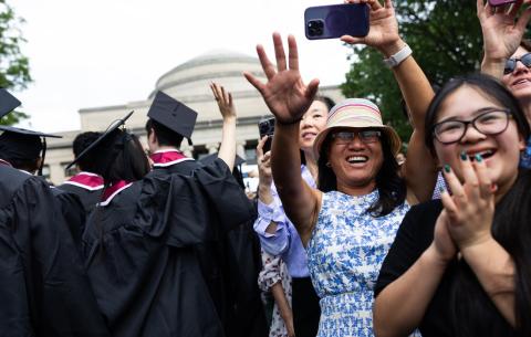 Image of parents waving to the graduates during the graduate procession