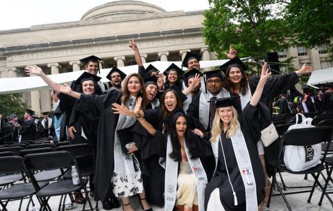 Image of the graduates in the audience smiling, with their arms up